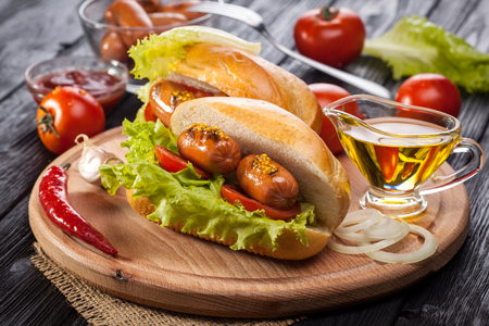Hot dog with Tomato, lettuce, Sausage, mustard, ketchup on the black wooden tableの写真素材