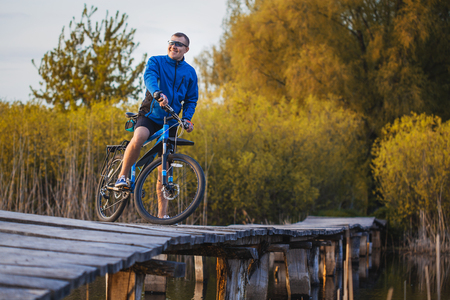 biking. man Rides on a wooden bridge across the riverの写真素材
