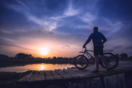 biking. man Rides on a wooden bridge across the riverの写真素材