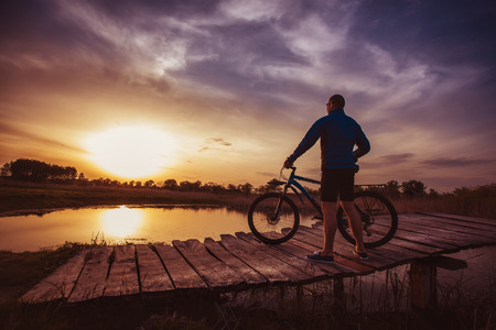 biking. man Rides on a wooden bridge across the riverの写真素材