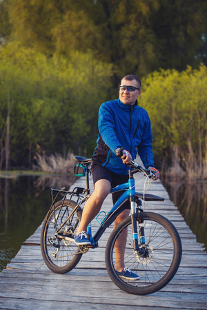 biking. man Rides on a wooden bridge across the riverの写真素材