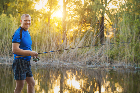 Fisherman with a spinning rod catching fish on a river. Man on a weekend.の写真素材