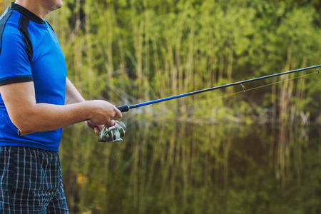 Fisherman with a spinning rod catching fish on a river. Man on a weekend.の写真素材