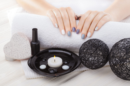 beautiful gray manicure with oil, candles and towel on the white wooden table. spaの写真素材