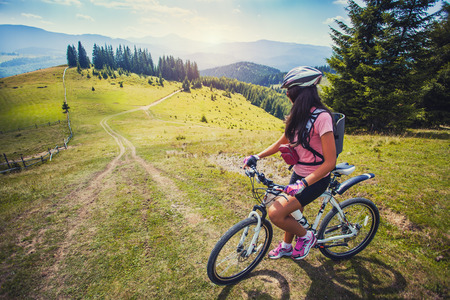 Happy young woman riding a mountain bicycle on the high plateauの写真素材