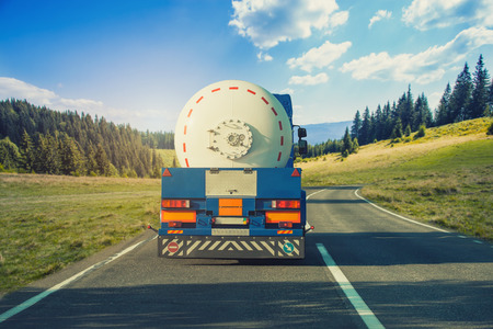 White tanker and trucks driving along the picturesque mountain highwayの写真素材