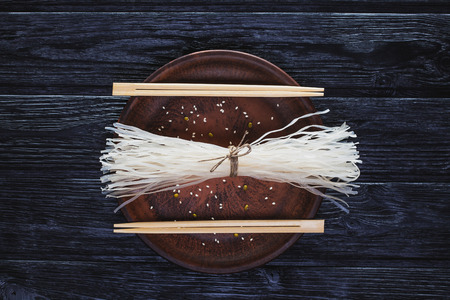 raw ingredients of oriental cuisine from rice noodles on a black wooden table.の写真素材
