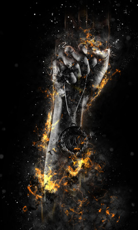 Man's hand in a fire is holding up gold medal on a dark background. Winner in a competition.の写真素材