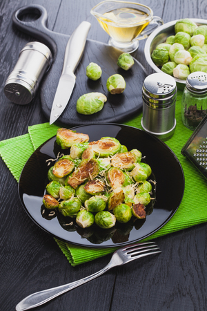 Roasted Brussel Sprouts with Parmesan cheese, lemon, Salt, Pepper on a black table.の写真素材
