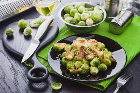 Roasted Brussel Sprouts with Parmesan cheese, lemon, Salt, Pepper on a black table.の写真素材