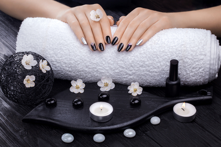 beautiful black manicure with apricot flower,candles and towel on the wooden table. spaの写真素材