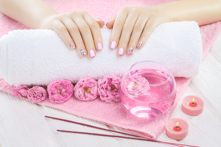 beautiful pink manicure with decor, tea rose, towel and candle on the white wooden table. spaの写真素材