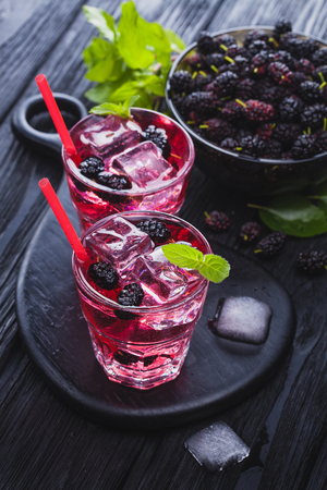 mulberry cocktail with ice and fresh mint on a black wooden table. refreshing summer drinkの写真素材