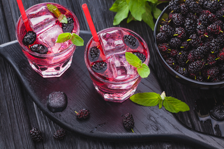 mulberry cocktail with ice and fresh mint on a black wooden table. refreshing summer drinkの写真素材