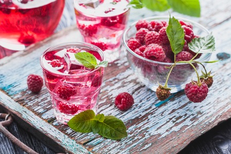 Red raspberries cocktail with ice and fresh mint on a old wooden tableの写真素材