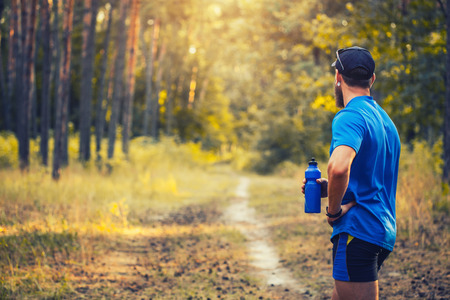 A bearded athlete prepares for a morning run along a picturesque forest pathの写真素材
