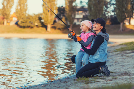 mother and daughter are fishing on the lake.の写真素材