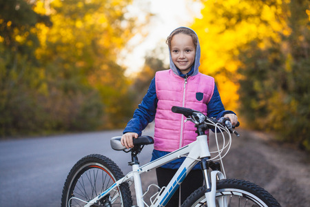 kid on a bicycle in the sunny autumn forest. girl cycling outdoorsの写真素材
