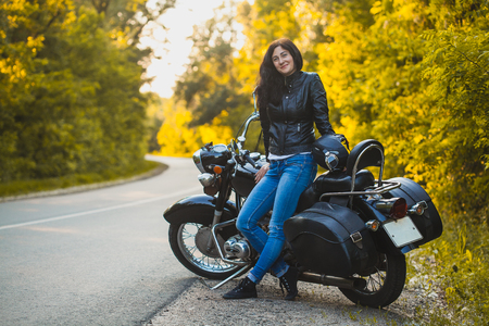 attractive brunette motorcyclist sits on a motorcycle.の写真素材