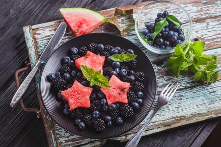 Frock blueberry, blackberry, watermelon and mint salad on an old wooden tableの写真素材