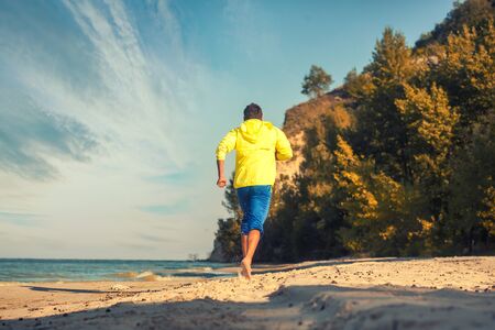 bearded athlete runs along the sandy beach.の写真素材