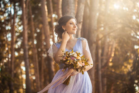 happy bride with a bouquet is walking the green parkの写真素材