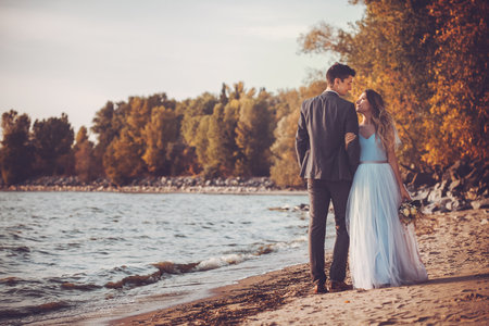happy bride and groom are walking on the autumn beachの写真素材