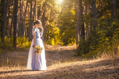 happy bride with a bouquet is walking the green parkの写真素材