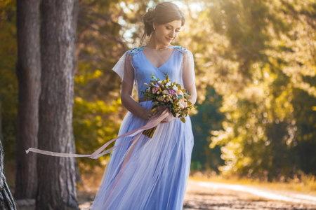 happy bride with a bouquet is walking the green parkの写真素材