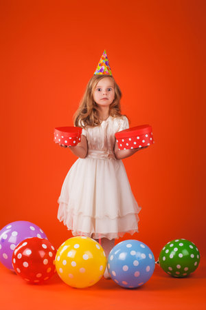 Cute girl in santa claus hat opens christmas presents. isolated on the whiteの写真素材