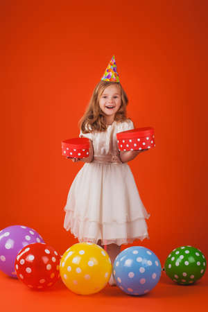 Cute girl in santa claus hat opens christmas presents. isolated on the whiteの写真素材