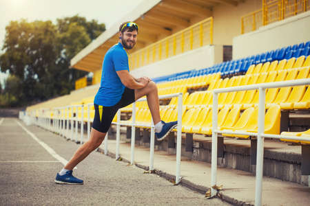 happy bearded male athlete is training in the stadiumの写真素材