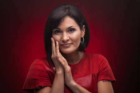 Brunette woman with shiny hair. beautiful model on red background. studio photosessionの写真素材