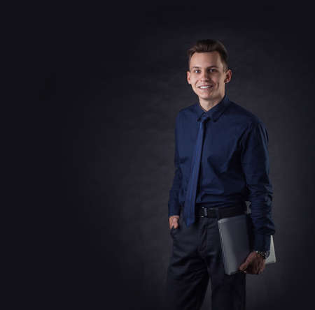 Successful business man on a dark background with a laptop. Sales Managerの写真素材
