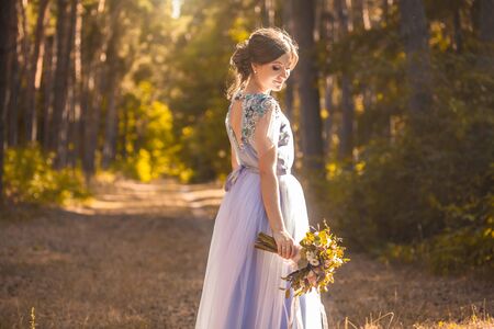 bride with a bouquet is walking the green parkの写真素材