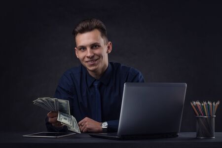 Successful business man on a dark background with a moneyの写真素材