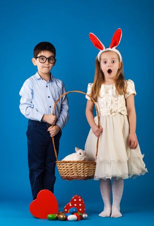 Cute boy and girl with White rabbit in basket with Easter eggsの写真素材