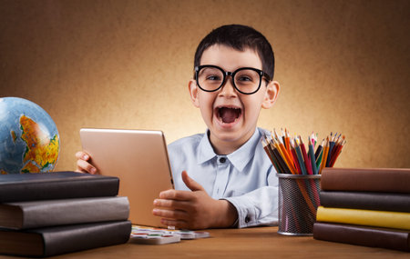 cute little boy schoolboy doing homework at a table with books