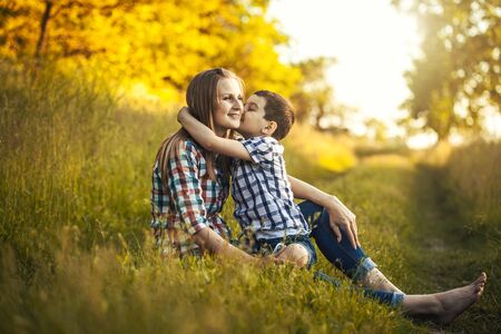 happy mom and son are playing on a summer green meadowの写真素材