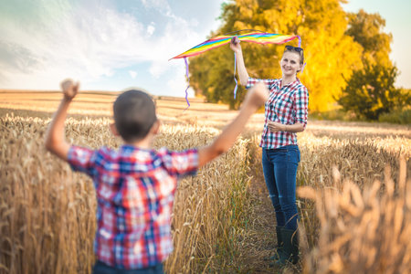 mom and son fly a kite in a summer wheat field. happy familyの写真素材