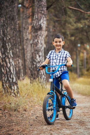 Happy kid cyclist rides in the forest on a bike.の写真素材