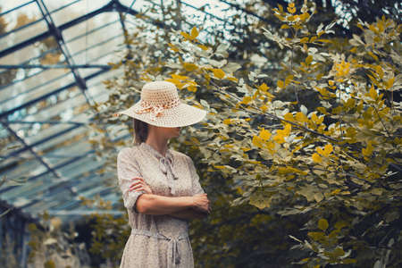 woman flowers in a retro dress and a hat in a old greenhouseの写真素材