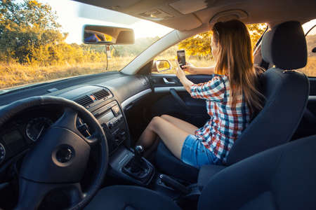 young woman makes selfie on the phone from the car window.の写真素材