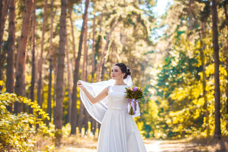 bride with a bouquet is walking the green parkの写真素材