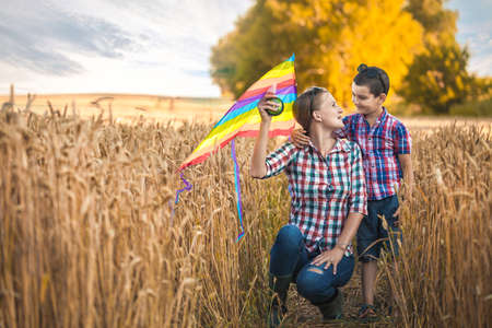 mom and son fly a kite in a summer wheat fieldの写真素材