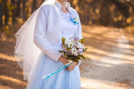 brides hands with flowers in on a background of autumn foliage.の写真素材