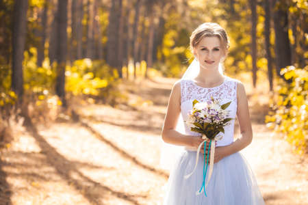 bride with a bouquet is walking the green parkの写真素材