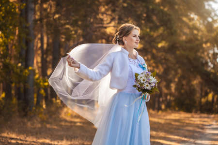 bride with a bouquet is walking the green parkの写真素材