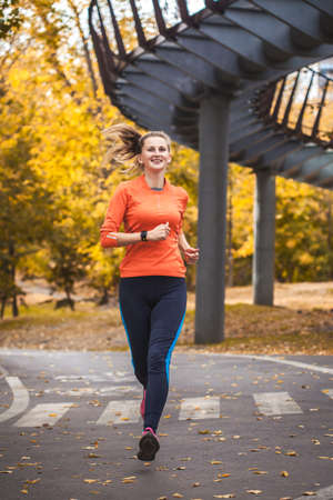 girl runner in autumn park in trainingの写真素材