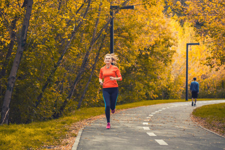 girl runner in autumn park in training